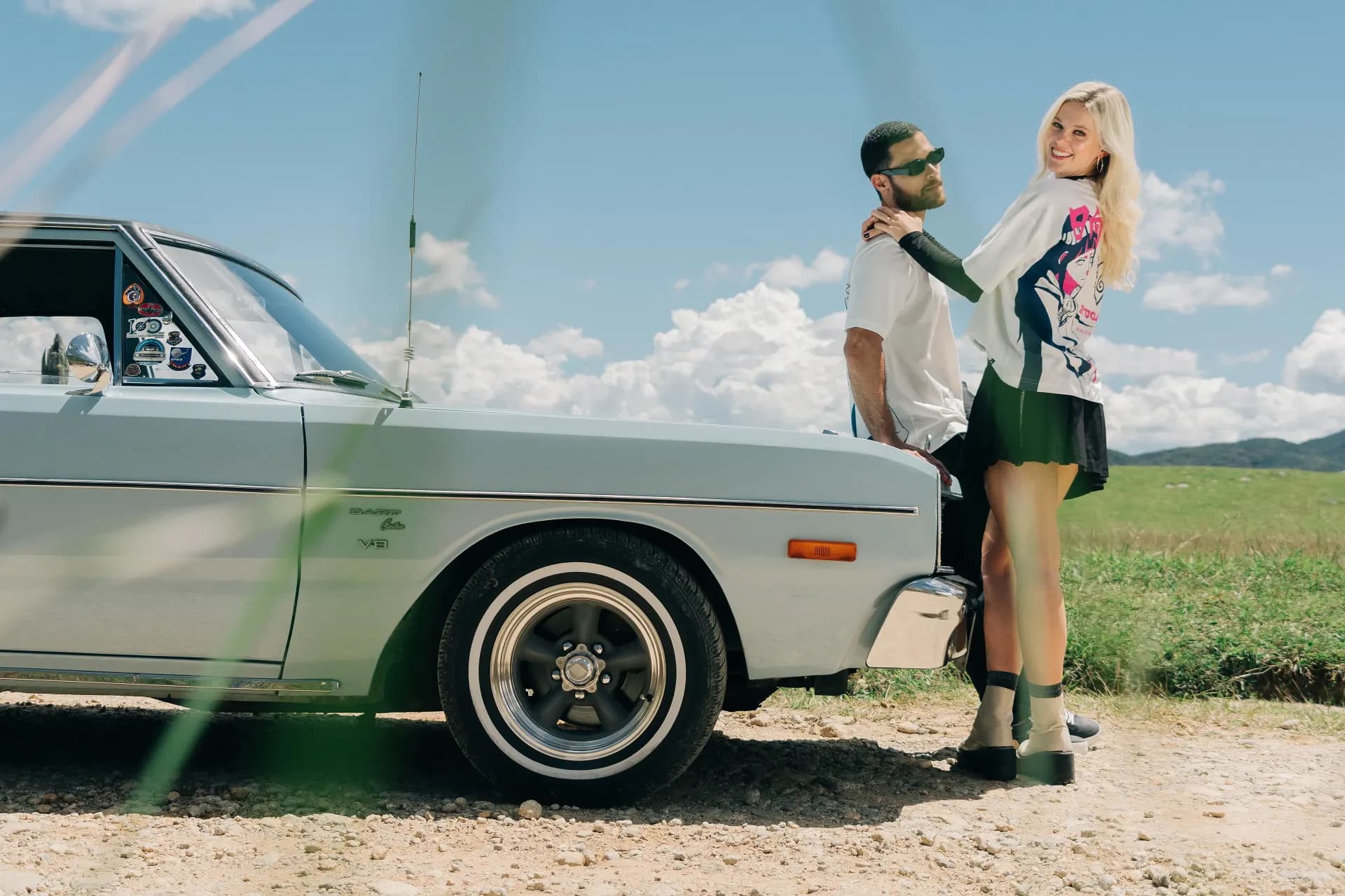 Fotografía editorial de la campaña TU PAR: pareja junto a un auto clásico plateado en un camino de tierra.