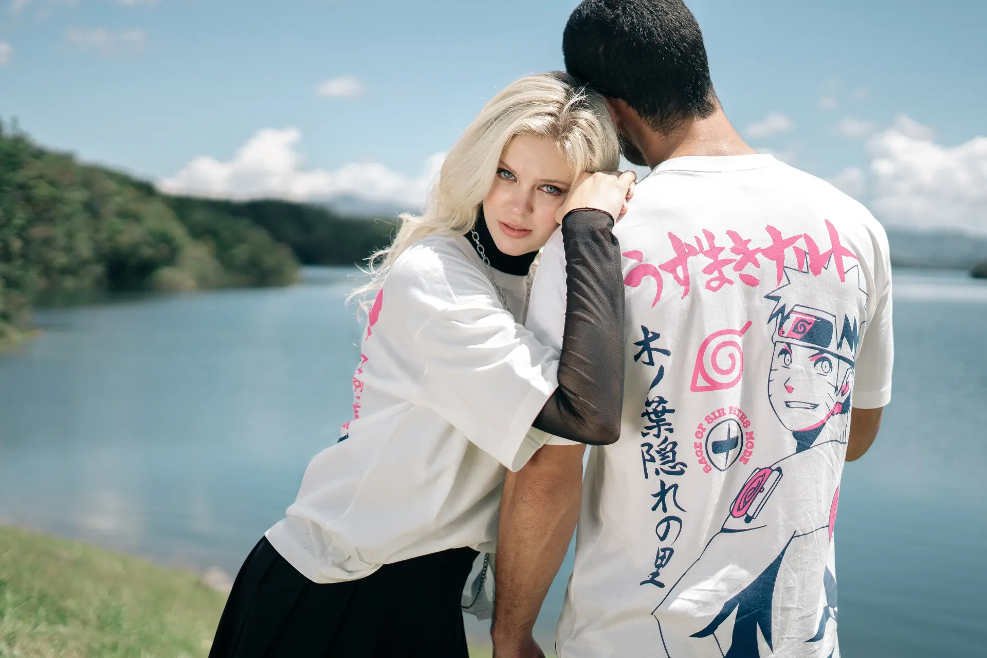 Fotografía editorial de la campaña TU PAR: pareja abrazada frente a un lago, ambos con camisetas blancas de anime.