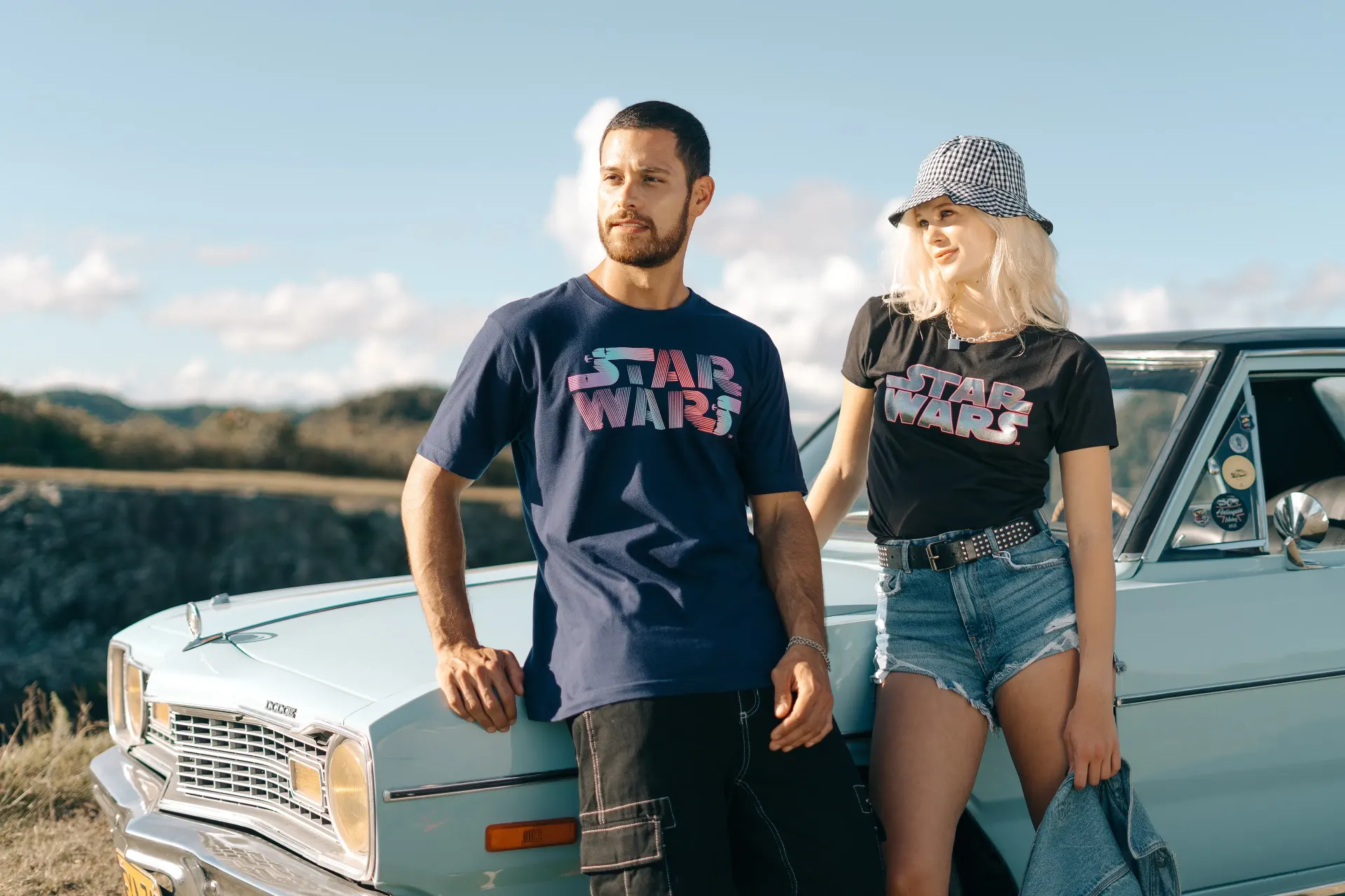 Fotografía editorial de la campaña TU PAR: pareja recostada en un auto clásico celeste, ambos con camiseta de Star Wars y ella con gorra.