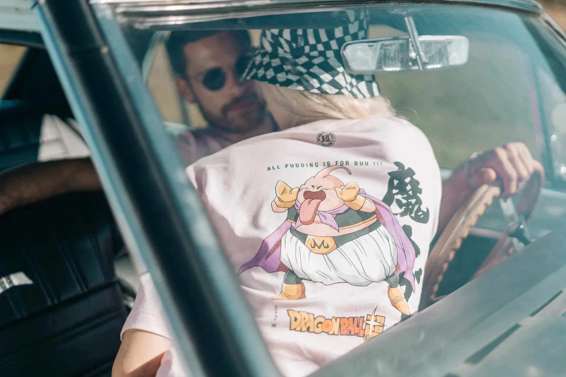Fotografía editorial de la campaña TU PAR: hombre al volante de un auto clásico, con gafas de sol y camiseta blanca con estampado de Dragon Ball.