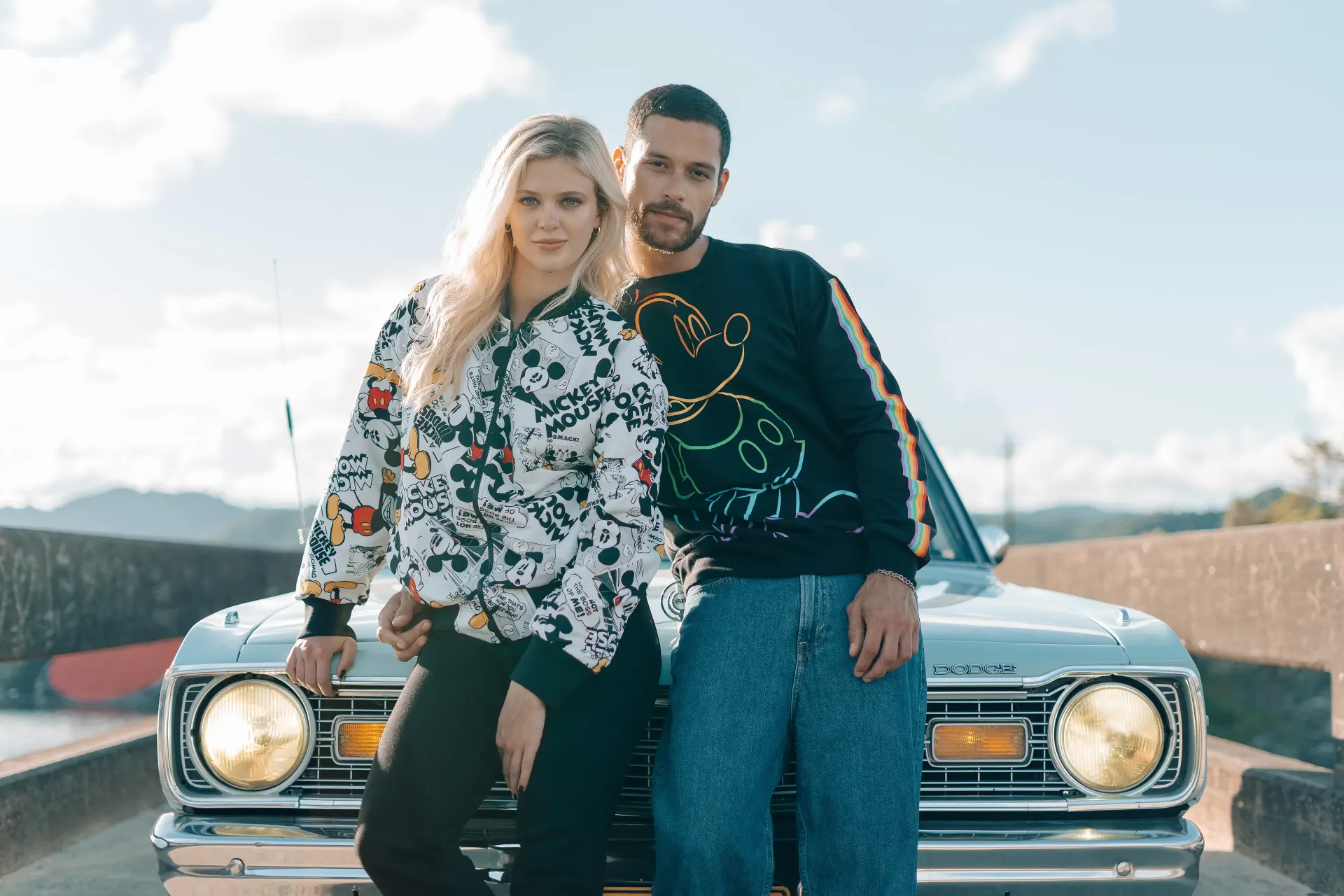 Fotografía editorial de la campaña TU PAR: la pareja frente a un auto clásico con el faro encendido, ella con camisa blanca de estampado de cómic.